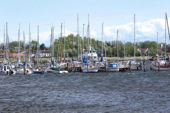 Eine Marina mit verschiedenen Schiffen, umgeben von Gebäuden und Grünflächen.