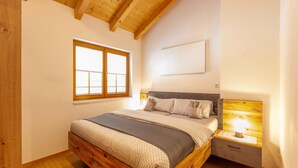 A bedroom with a wooden bed, a nightstand, a window, and a wall-mounted light fixture.