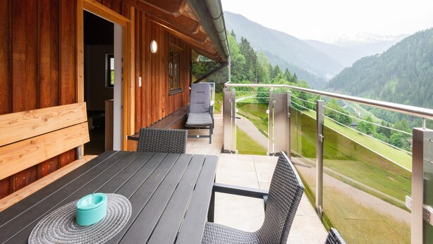 A wooden cabin with a balcony overlooking a mountainous landscape.