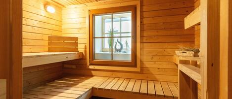Een houten sauna met banken en een raam.