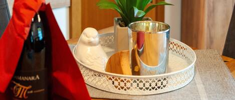 A bottle of wine, a bird-shaped salt shaker, a small potted plant, and a metal cup on a tray.