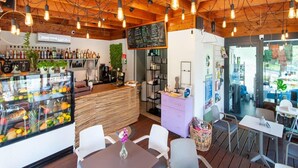 A restaurant interior with wooden ceiling beams, hanging light bulbs, a fruit display case, a chalkboard menu, and a seating area with tables and chairs. - Spacious Holiday Homes With air Conditioning, Pool (Rewal)