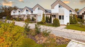 A row of modern, single-story houses with a uniform architectural style, featuring large windows and a flat roof. - Spacious Holiday Homes With air Conditioning, Pool (Rewal)