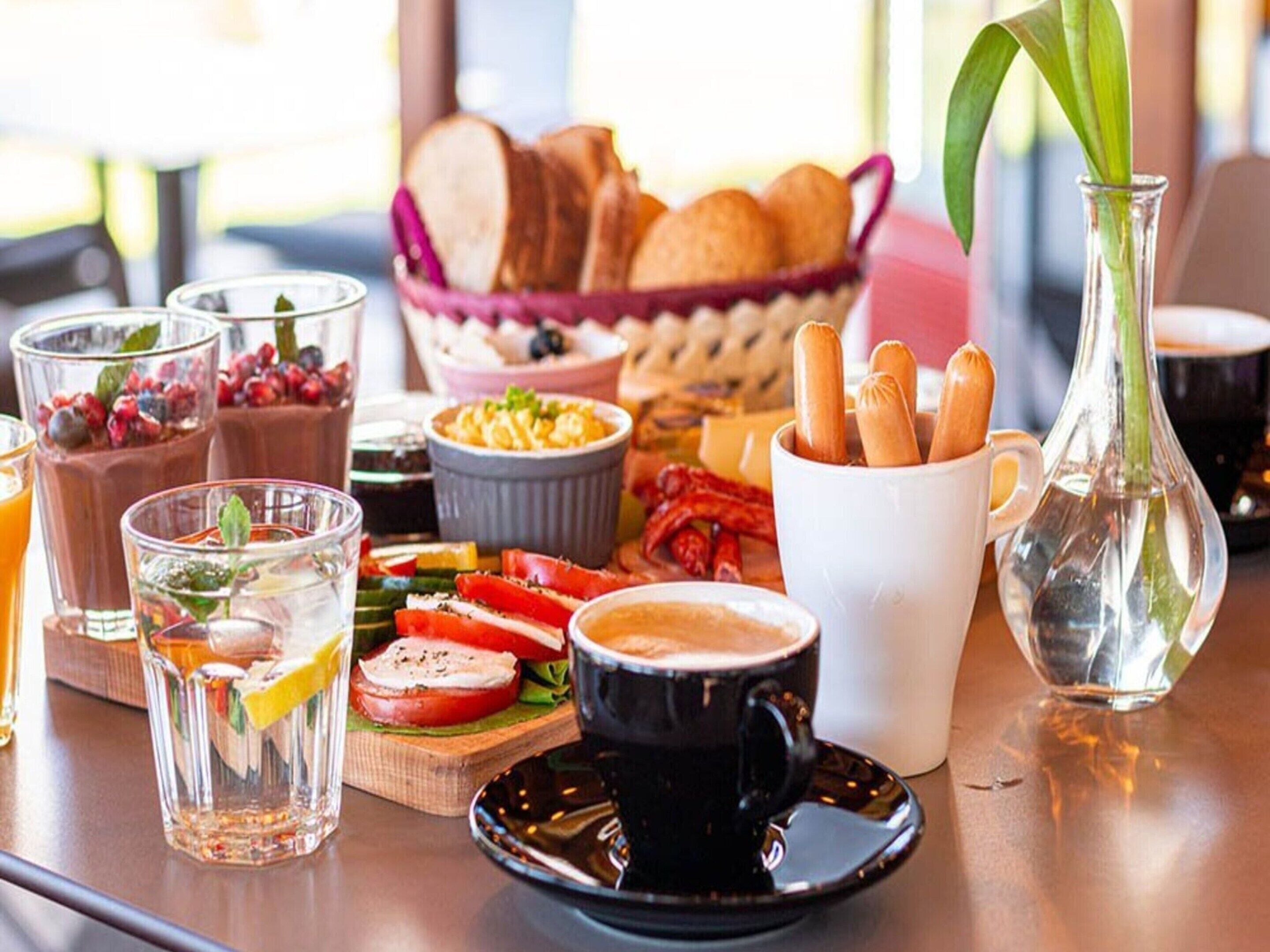 Een tafel met verschillende soorten eten, drinken en een bloevas.