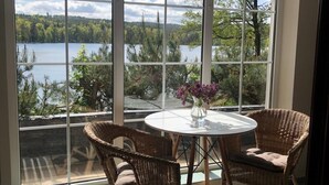 A room with a large window overlooking a lake, furnished with wicker chairs and a round table. - A Wonderful Holiday Home With Lake Access (Wejherowo)