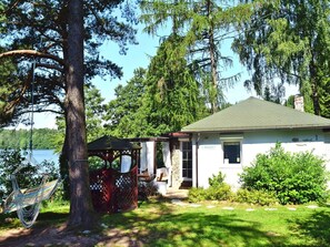 Una casa con porche cubierto, una hamaca y vista al lago.