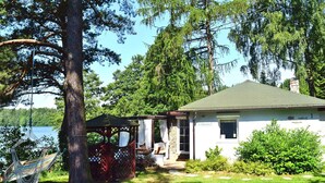 A house with a covered porch, a hammock, and a view of a lake. - A Wonderful Holiday Home With Lake Access (Wejherowo)