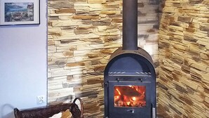 A room with a stone wall, a fireplace, and a basket on the floor. - A Wonderful Holiday Home With Lake Access (Wejherowo)