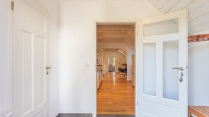 A hallway with wooden flooring, white walls, and a door leading to a room with a bench. - Historisches Reetdachhaus in Ruhiger Lage (Tating)
