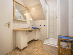 Un baño moderno con ducha, lavamanos y espejo.