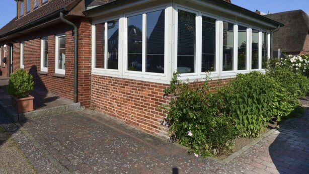 A two-story brick house with a large bay window and a conservatory. - Ferienwohnung in Wyk-boldixum auf Foehr (Wyk auf Foehr)