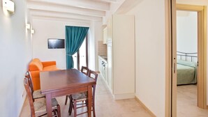 A dining area with a wooden table and chairs, a sofa, and a TV mounted on the wall. - Holiday Resort Contea dei Ciliegi, Pedaso (Pedaso)