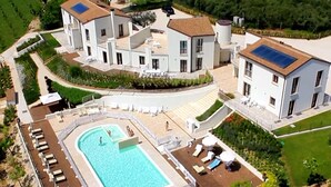 A large, modern hotel with a central swimming pool surrounded by sun loungers and a fenced deck area. - Holiday Resort Contea dei Ciliegi, Pedaso (Pedaso)