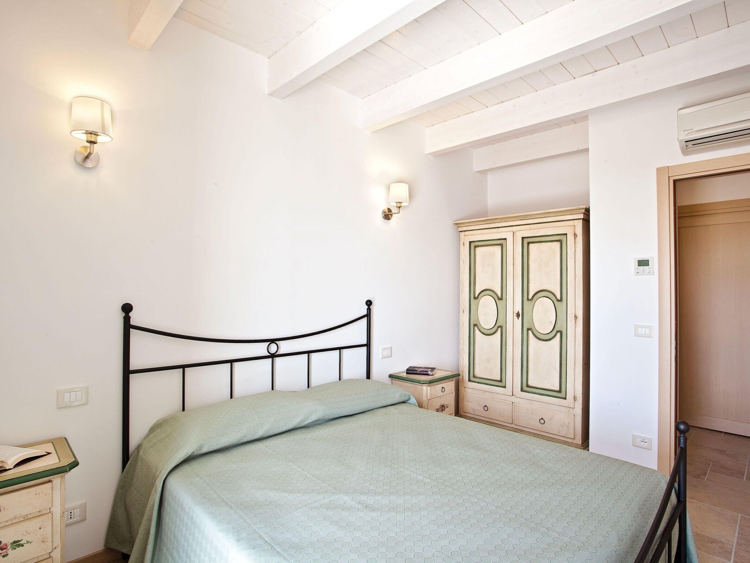 Un dormitorio con cama, mesita de noche, cómoda y armario.