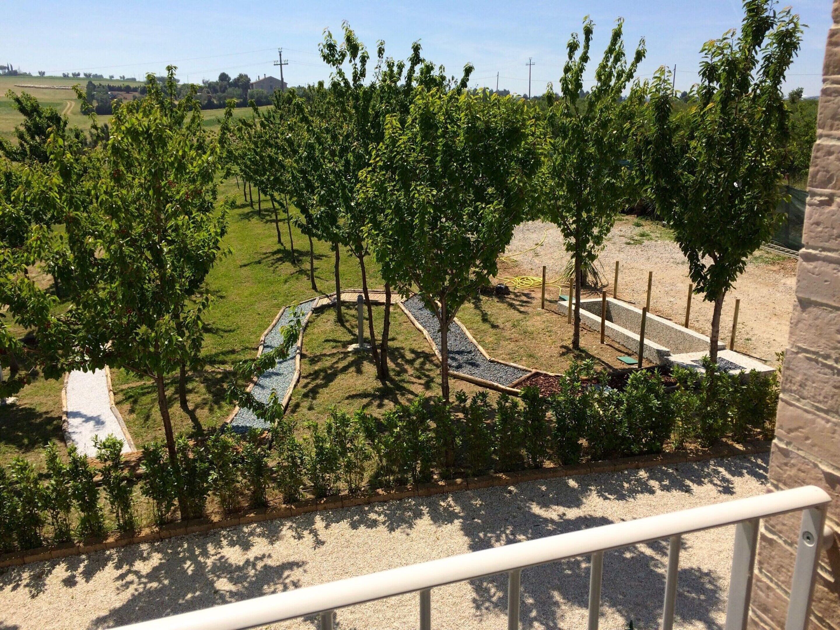 A landscaped garden with a gravel path, trees, and a brick wall.