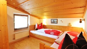 A cozy wooden cabin room with a bed, a window, and a radiator. - Apartment in Bramberg Near Wildkogel Arena (Bramberg am Wildkogel)