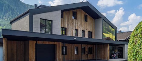 Un edificio moderno de dos pisos con techo plano, ventanas amplias y una combinación de madera y hormigón.