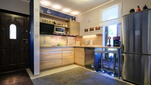 A modern kitchen with wooden cabinets, a stainless steel refrigerator, a microwave, and a coffee maker. - Holiday Home in Lukecin Near Baltic Beach (Dziwnów)