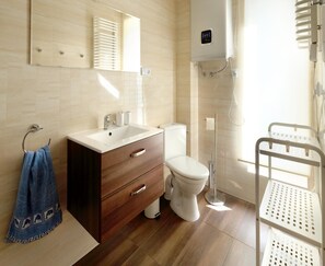 Een moderne badkamer met een houten wastafel, toilet, douche en handdoekrek.