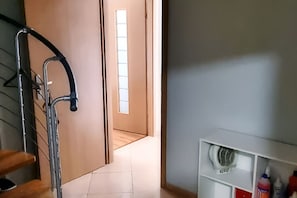 Un couloir avec un porte-vélo, une porte donnant sur une autre pièce et une étagère contenant des produits de nettoyage.