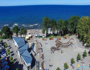 An aerial view of a coastal promenade with a large metal sculpture, a parking lot, and a view of the sea. - Chalet in Rewal Near Baltic Sea Beach (Rewal)