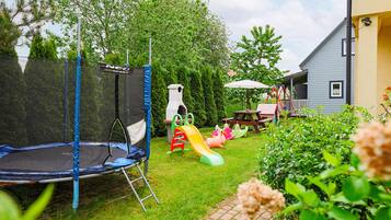 Patio trasero con un trampolín, estructuras de juego y una mesa de picnic.