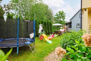 Ein Garten mit Trampolin, Spielgeräten und einem Picknicktisch.