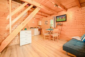 Ein Holzblockhaus-Innenraum mit Essbereich, Küche und einer Treppe.