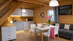 A cozy cabin interior with a dining area, kitchen, and living space.