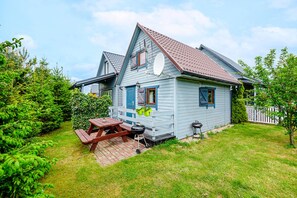 A two-story house with a sloped roof, a satellite dish, and a wooden deck with a picnic table. - Chalet in Rewal Near Baltic Sea Beach (Rewal)