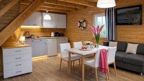 A cozy cabin interior with a dining area, kitchen, and living space. - Chalet in Rewal Near Baltic Sea Beach (Rewal)