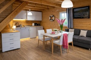A cozy cabin interior with a dining area, kitchen, and living space. - Chalet in Rewal Near Baltic Sea Beach (Rewal)