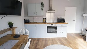 Una cucina moderna con mobili bianchi, forno integrato e un'ampia finestra.