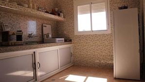 Eine Küche mit gefliesten Wänden, einem Fenster und einem Kühlschrank.