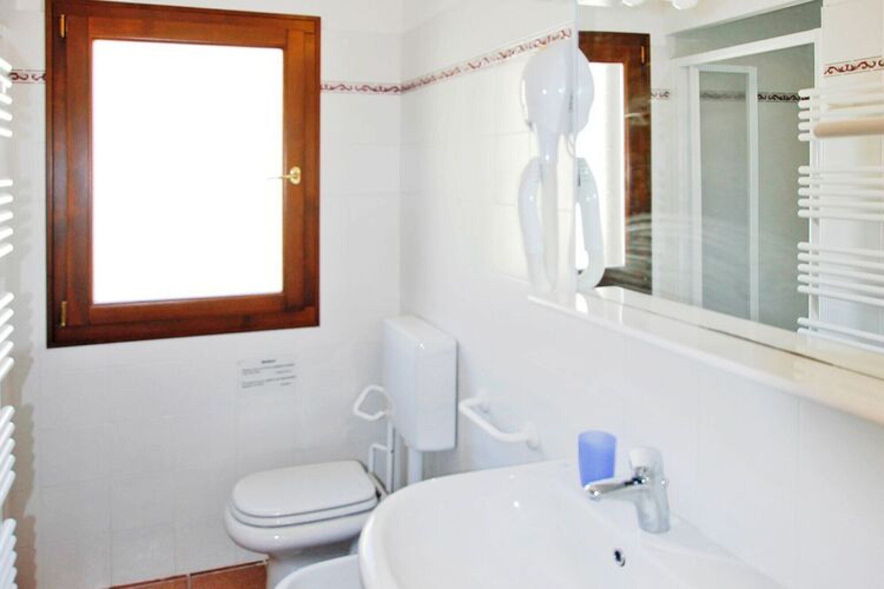 Une salle de bain avec des toilettes, un lavabo et une fenêtre située au-dessus du lavabo.