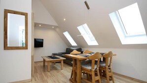 Un loft moderno con comedor, sofá y televisor montado en la pared.