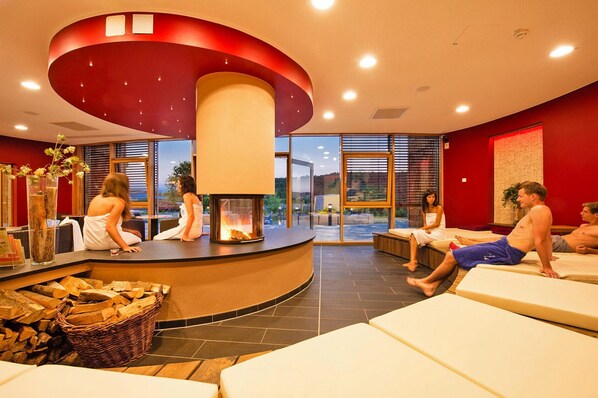 A spa area with a central fire feature, seating areas, and a view of the outdoors.
