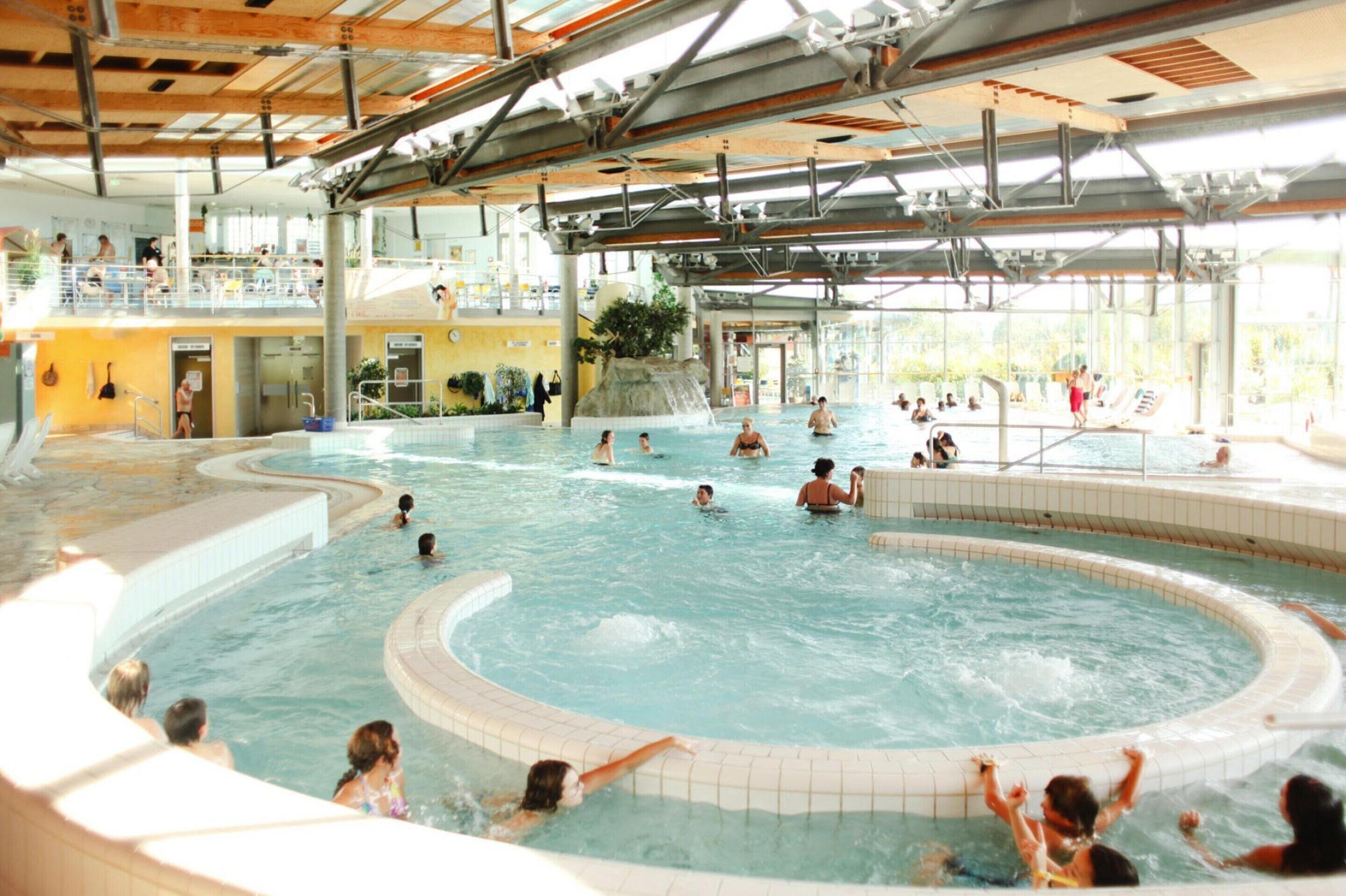 Une grande piscine intérieure dotée de plusieurs couloirs et d’un élément décoratif central.
