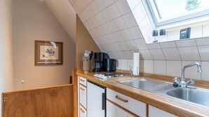 A modern kitchen with a wooden countertop, stainless steel sink, and a skylight above.