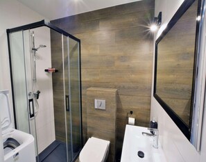 Une salle de bain moderne avec une douche à parois de verre, un lavabo blanc et un grand miroir.