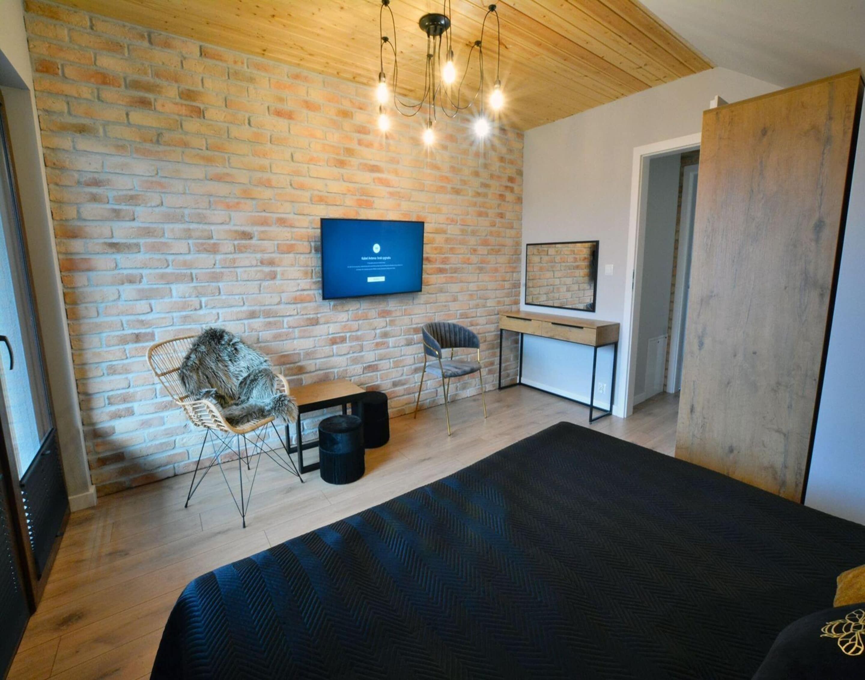Une chambre à coucher moderne avec un mur en briques, un lit, un bureau et une chaise.