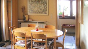 Un comedor con una mesa redonda de madera, seis sillas y un jarrón central.