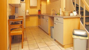 Una cocina compacta con comedor, un reloj, cafetera y un bote de basura.