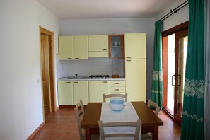A compact kitchen with a dining table and chairs, a sink, and a stove. - Flat With Communal Pool in the Residence Badus in Badus-formerly TUI Ferienhaus (Badesi)