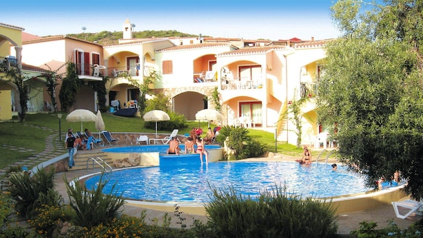 A pool area with multiple pools, lounge chairs, and umbrellas. There are people relaxing and swimming. - Flat With Communal Pool in the Residence Badus in Badus-formerly TUI Ferienhaus (Badesi)