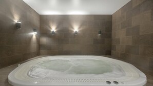 Une salle de bain moderne avec une grande baignoire, un éclairage encastré et des murs carrelés.