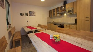 A kitchen with wooden cabinets, a microwave, and a dining area with benches and a red runner. - Ferienwohnung im Haus Schiefertal, Wieda (Walkenried)