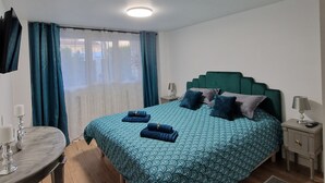 Een slaapkamer met een bed, nachtkastjes, een bureau en een raam met gordijnen.