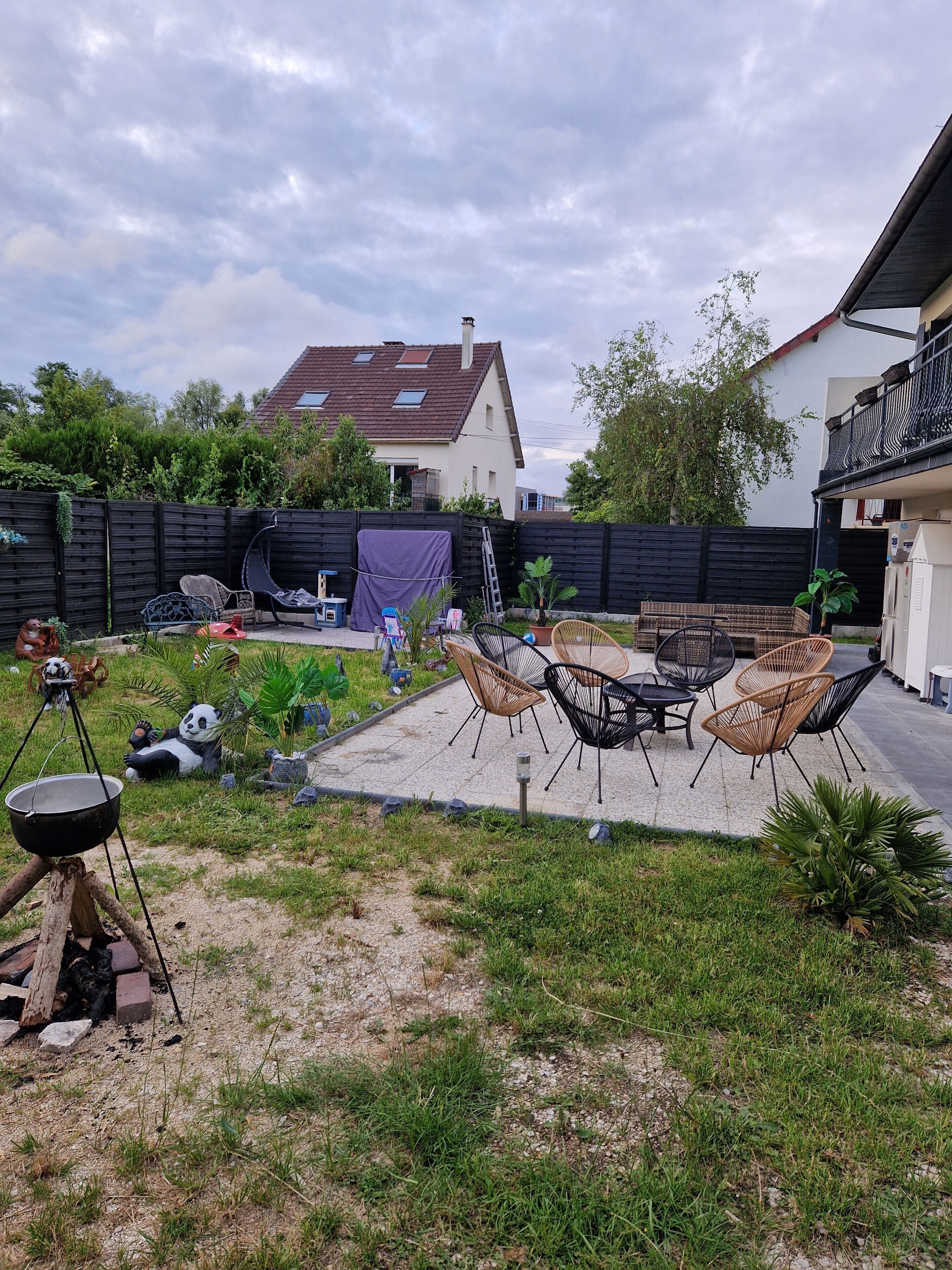 Ein Garten mit Gartenmöbeln, einem Grill und einem überdachten Bereich.