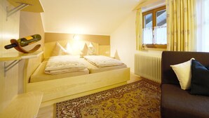 Ein Schlafzimmer mit einem Bett, einem an der Wand montierten Fernseher, einem Heizkörper, einem Fenster mit Vorhängen und einem Sofa.